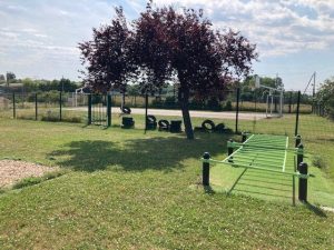 Extérieur du CEF, montrant une structure de parcours métallique et un stade multisport, dans un cadre verdoyant.