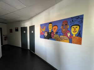 Couloir du DAMIER, montrant une peinture réalisée par les jeunes du DAMIER, donnant sur des bureaux