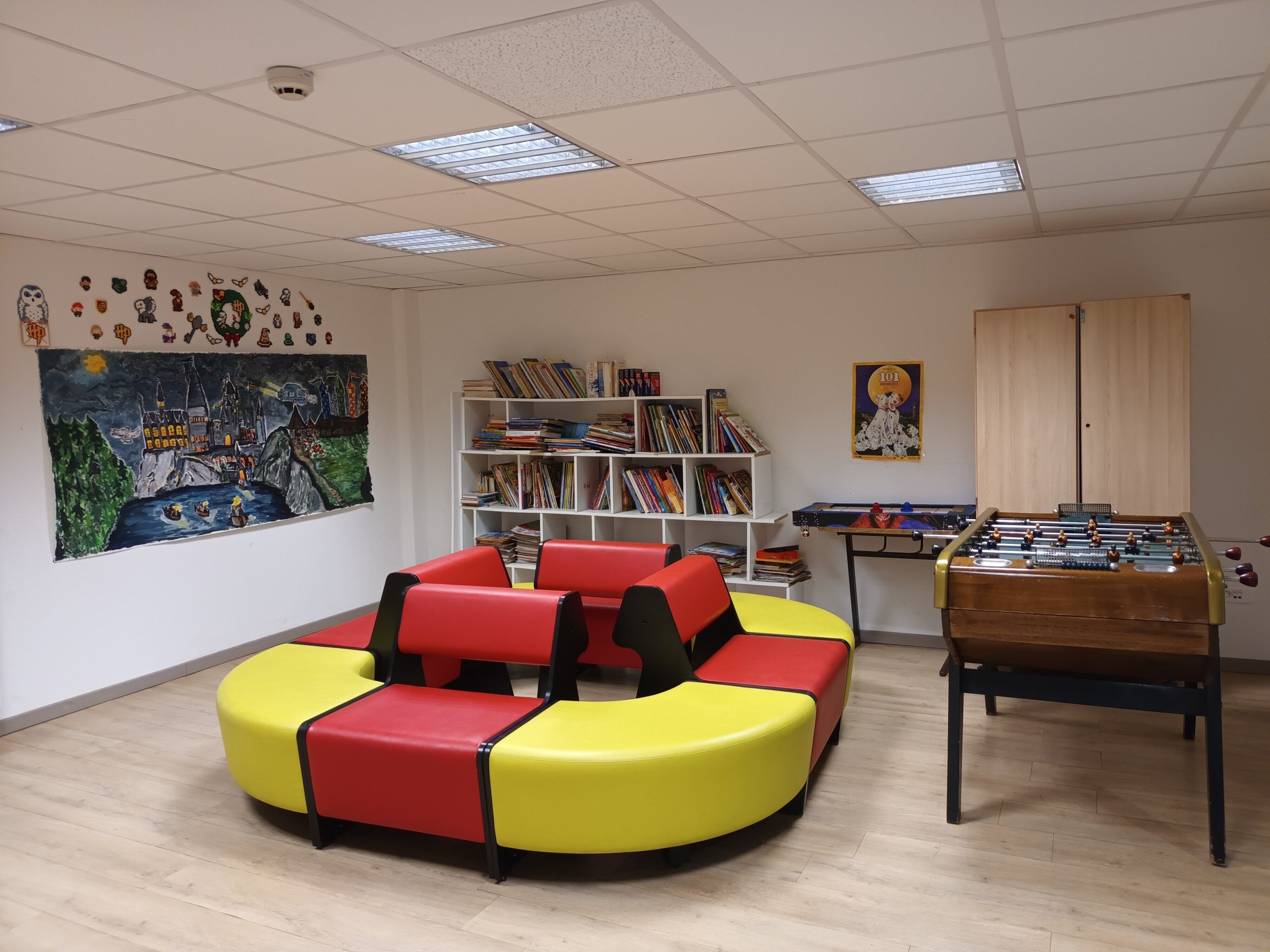 Salle de vie commune du DITEP l'Escale, montrant un canapé, une bibliothèque remplie de livres et un babyfoot