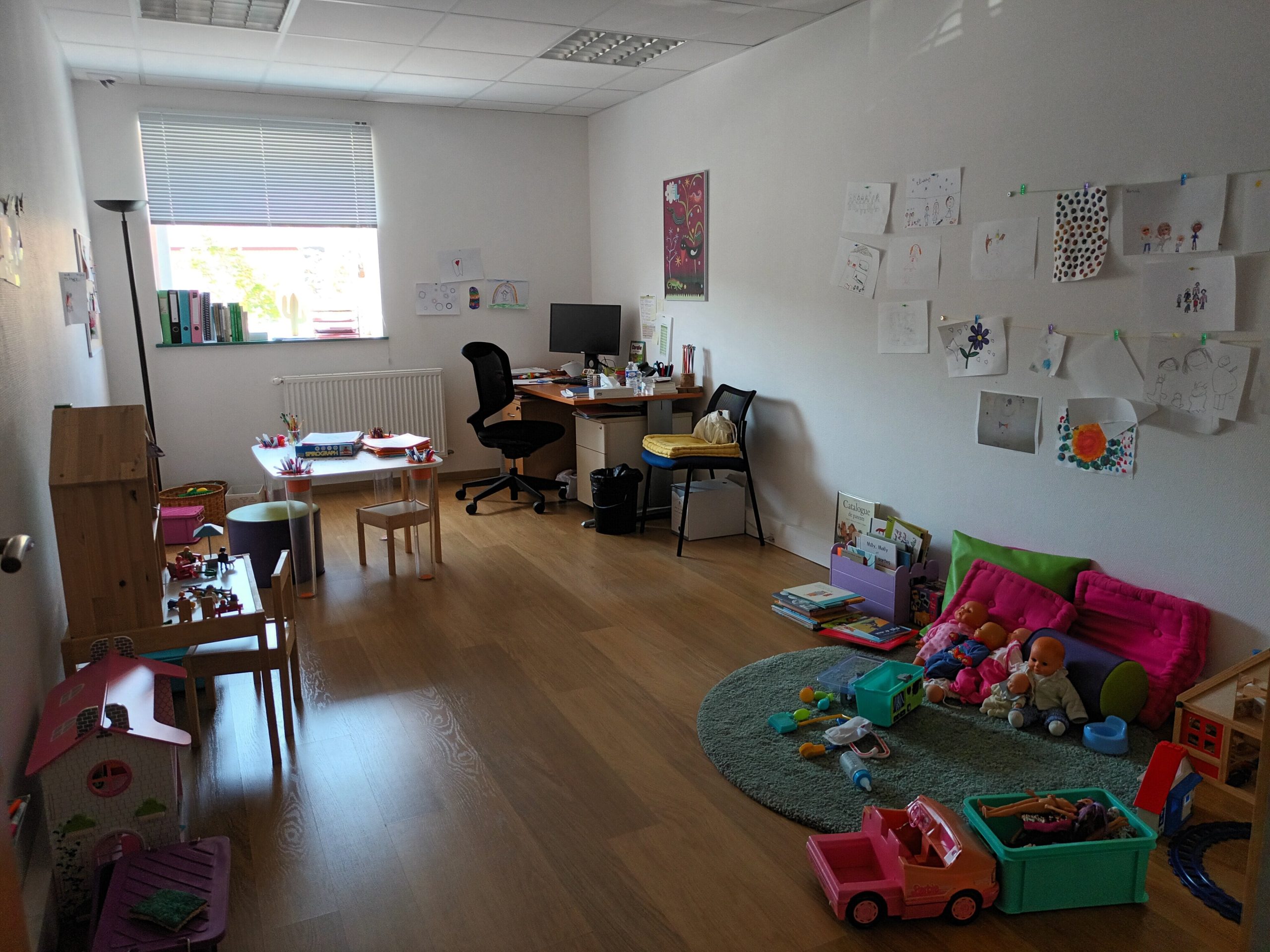 Bureau professionnel du SAPFR montrant un poste de travail, des jouets pour enfants, adaptés pour des enfants en bas âge, des dessins sur les murs