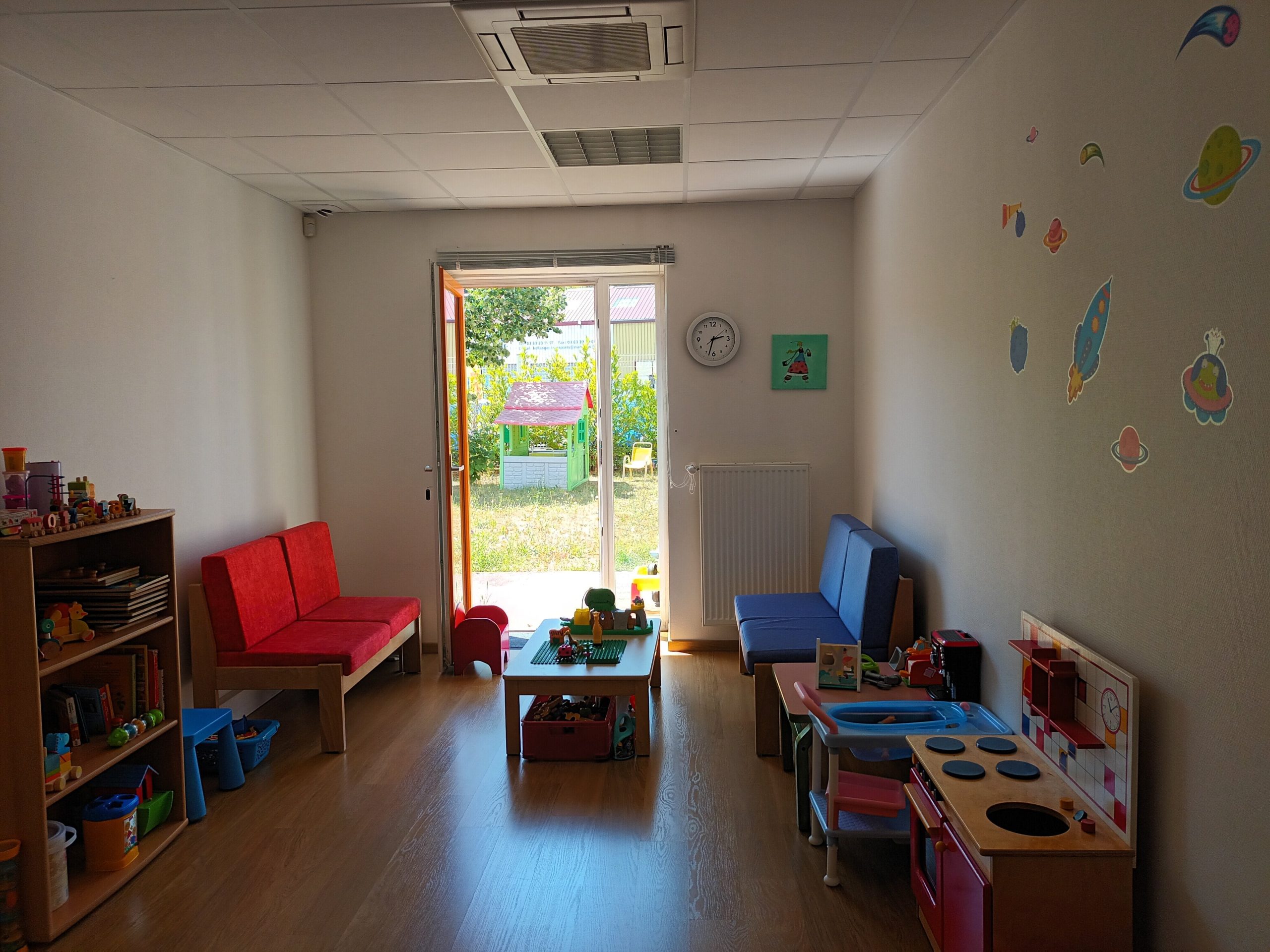 Salle de vie du SAPFR montrant des jouets pour enfants, adaptés pour des enfants en bas âge, des canapés avec un fenêtre donnant sur un extérieur verdoyant