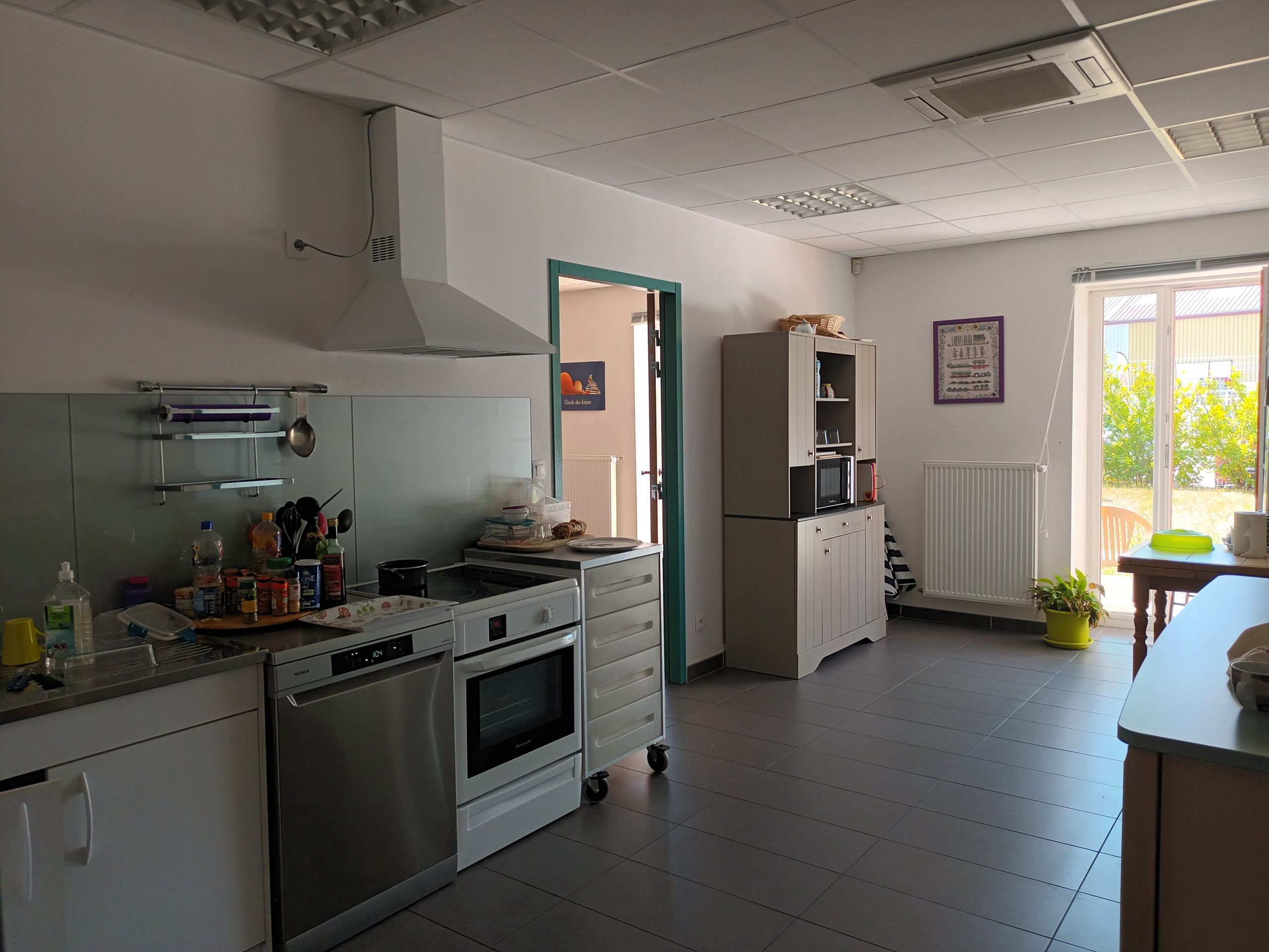 Salle de vie du SAPFR montrant une cuisine équipée avec une fenêtre donnant sur un extérieur verdoyant