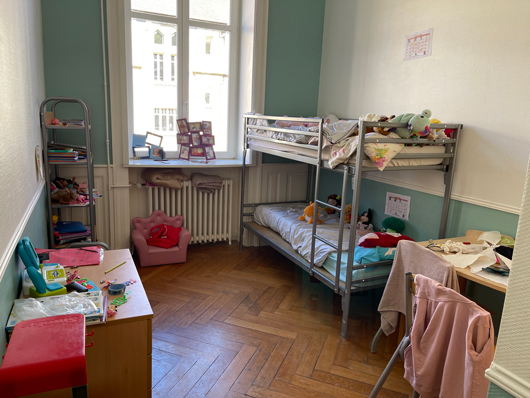 Chambre double de la MECS du Domaine de l'Asnée, montre un lit suspendu, un bureau, une étagères avec des effets personnels, avec une fenêtre.