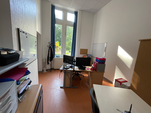 Bureau professionnel de la MECS du Domaine de l'Asnée, montrant un poste de travail, une table ronde et des chaises pour recevoir du public extérieur avec une fenêtre